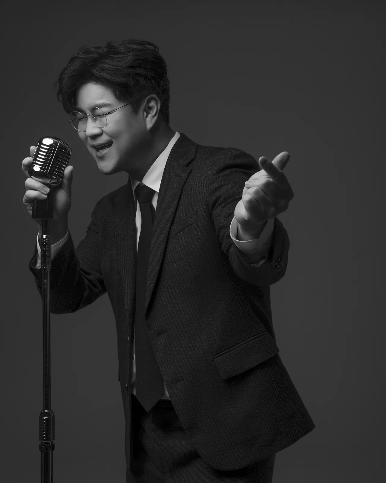 마이크 스탠드 앞에서 손을 뻗어 노래하는 박구윤